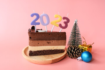 Chocolate cake with numbers 2023  and accessories for Christmas and new year event isolated on pink background.
