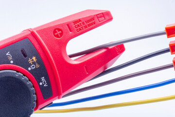 The electrician measures the current in the phase wire with a meter