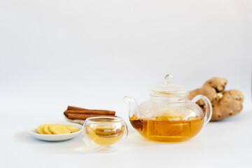 a cup of tea with ginger root, lime, cinnamon and teapot on white background. Health drink concept..