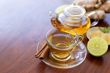 a cup of tea with ginger root, lime, cinnamon and teapot on white background. Health drink concept.