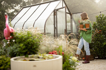 Woman with plants near greenhouse at backyard