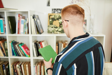 Back view of young man buying used books in thrifting shop or swap event