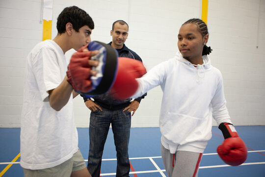 Sports Students: Kickboxing. Teenage boys learning martial arts skills under the supervision of her teacher. From a series of related images.