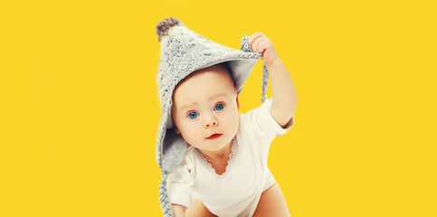 Portrait of cute little baby wearing gray knitted hat on yellow background