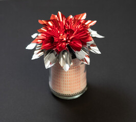 Lottery ticket as a gift in a jar with red silver bow, isolated on black background. Lottery ticket gift ideas. 