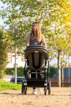 Mother and son walking with the baby stroller in the park