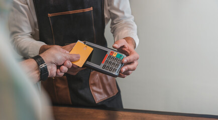 Detalle de mano, de cliente pagando con tarjeta bancaria, en el datafono al irreconocible...