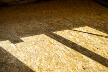 Shade from the sun on the floor of osb panels. Shadow from the window of the setting sun at a...