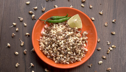 Sprouted matki or moth bean which is rich in protein and vitamins in plate with lemon and chilly.