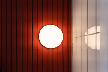 Beautiful modern round shape wall lamp light bulb decoration for home and living on the red and white wall background with copy space for text.