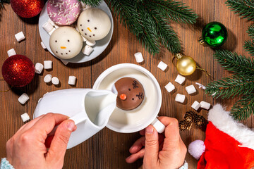 Making winter hot drink, preparation funny Christmas characters with hot chocolate bomb. Homemade...