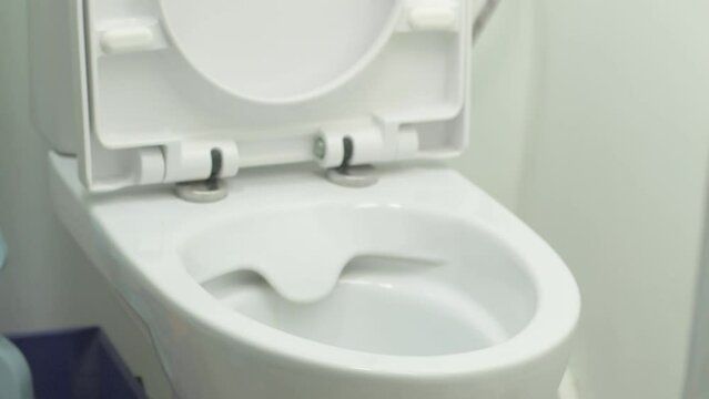 A Man's Hand Lifts A Plastic Toilet Seat.