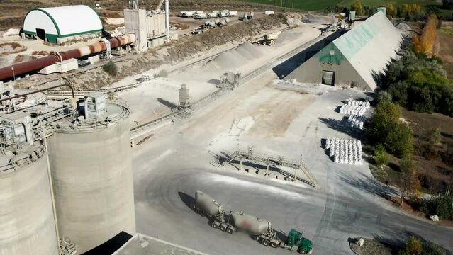 Aerial pan left shot of Industrial Complex with Silos and a Semi Truck driving in the background