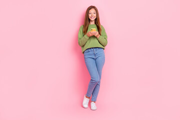 Full length photo of positive cute school girl dressed green sweatshirt typing instagram twitter...