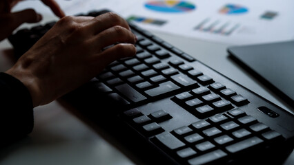 Business woman working late at office at computer typing on keyboard. Female using computer for financial reports, working late overtime