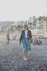Fototapeta premium Young beautiful girl on an autumn sunny day walks on the beach of the Mediterranean Sea