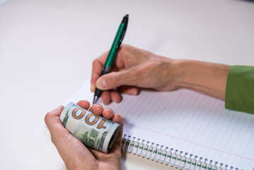 hand holding pencil and many american dollar