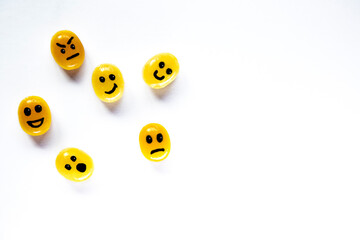 Yellow candies with painted emoji faces ot it on the white background
