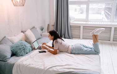 Young asian woman using laptop on bed at home