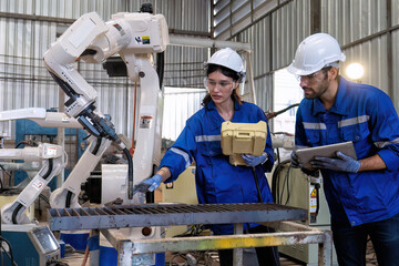 In robotic training center instructor use tablet pc teach girl engineer how to program robot arm