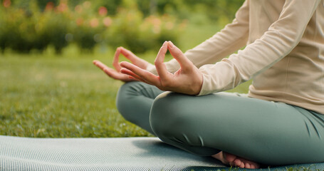 Woman practices yoga and meditates in lotus position. Healthy female girl sits in pose of lotus meditating or practicing yoga in nature. Meditation practices. Yoga healthcare concept.