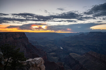 Desert landscape of the famous Grand Canyon at dusk, there are clouds and the orange sky