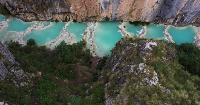 Beautiful overhead aerial shot zoom in with a drone from the Andes area of the famous turquoise Lake Millpu located between mountains in the afternoon located in Ayacucho, Peru.