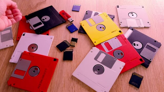 vintage retro electronic data storage devices from the 80s, 90s, cd disk, flash drives scattered on table. Stack of floppy disks, pendrive and hard disk in grey, black, blue, yellow, red, white