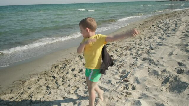 The boy is a super hero on the sea. Super hero on the beach.