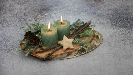 Adventsdekoration mit grünen Kerzen auf einer Baumscheibe.