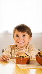 a young mother serves her son a healthy breakfast and sits next to the child to eat toast, cereals, nuts and a cup of milk to share as a family inside her home in the living room
