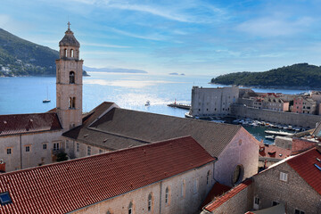 view to the slim tower above the Dominican Monastery with classic red tiled rooftops near the harbor in the old town of Dubrovnik, Croatia