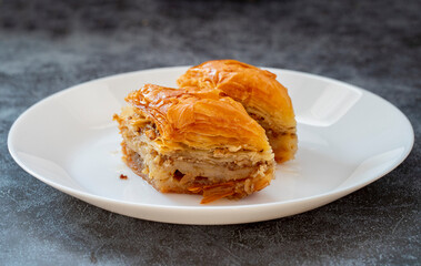 Baklava with pistachio in a white plate. Turkish style pistachio baklava presentation and service. Horizontal view.