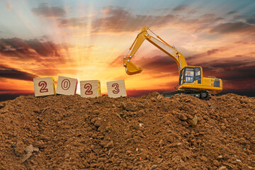 Concept Happy new year 2023,With Crawler excavator lift up bucket in construction site .On Sunset...