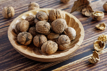 Walnuts in a wooden bowl on a rustic wooden table. Close-up view.