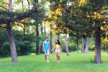 Young smiling couple walking down the footpath in the summer park