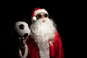 Santa Claus with sunglasses or a welder holding a World Cup soccer ball as a gift for all children,...