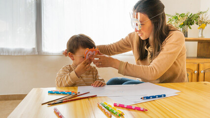 a young mother with her little son play with animal masks to share and enjoy family life inside their home in the living room smiling and having fun