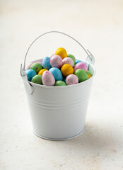 Colorful chocolate eggs in a small white bucket