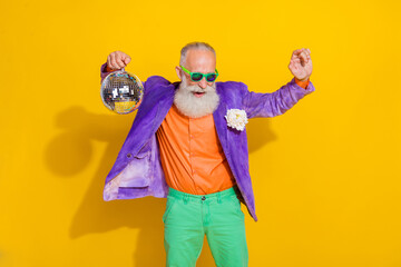 Photo of funky overjoyed grandfather hand hold disco ball have fun dancing isolated on yellow color...