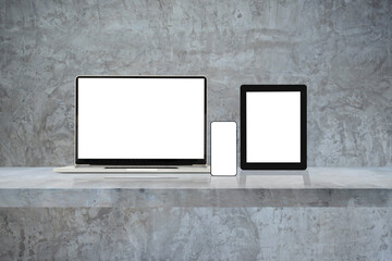Laptop, mobile phone and digital tablet pc on grey wall shelf.