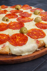 sabrosa pizza de pepperoni en tabla de madera con foondo negro