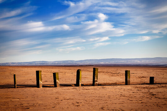 Wooden groynes on Berrow beach, with a shipwreck in the distance