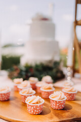 Gourmet cupcakes with white buttercream frosting and sprinkles on wooden background