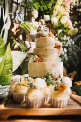 Gourmet cupcakes with white buttercream frosting and sprinkles on wooden background
