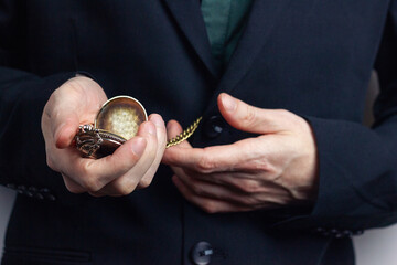Male hands of a businessman in a business suit with a ring on his finger hold a pocket old time....