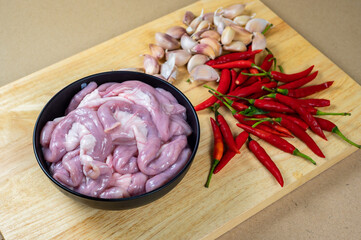 Raw pig intestine in a black bowl  with chilli and garlic lay on a wooden board, Uncooked ...