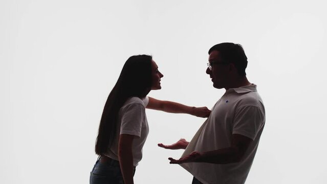 Young woman agressively blaming and pokes in the chest a man who refuses to accept her charges and yelling at her on white background. Couple swearing with each other during emotional quarrel