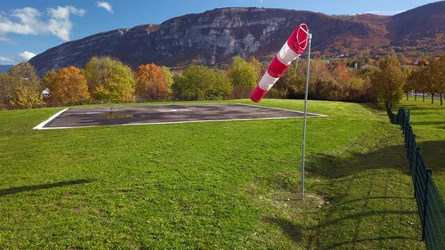 Windsock waves in the gentle fall wind breeze next to an helicopter FATO 4k