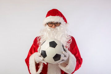 Santa Claus with glasses holding a World Cup soccer ball as a gift for all children, with a white background where his red suit and white beard stand out